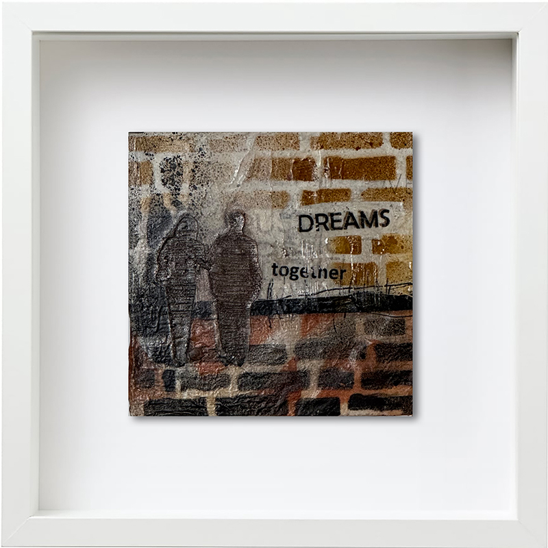 Unikat in mixedmedia technik mit weißen Rahmen, zwei schattenhafte Figuren vor einem Mauerartigen Hintergrund, Text Dreams together Brauntöne mit schwarz